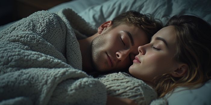 A couple cuddling peacefully in bed, showing non-sexual affection and security.