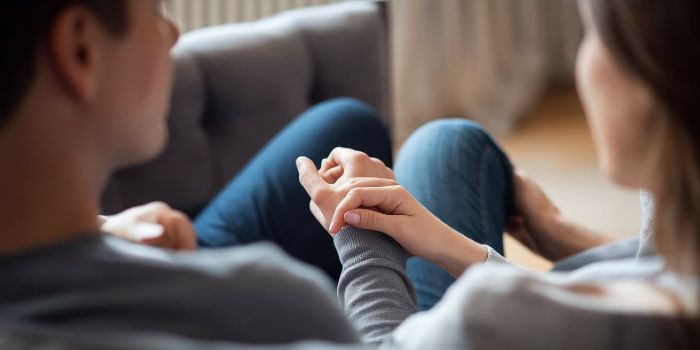 A close-up of a partner's hand on their loved one's arm, showing a supportive non-verbal cue.